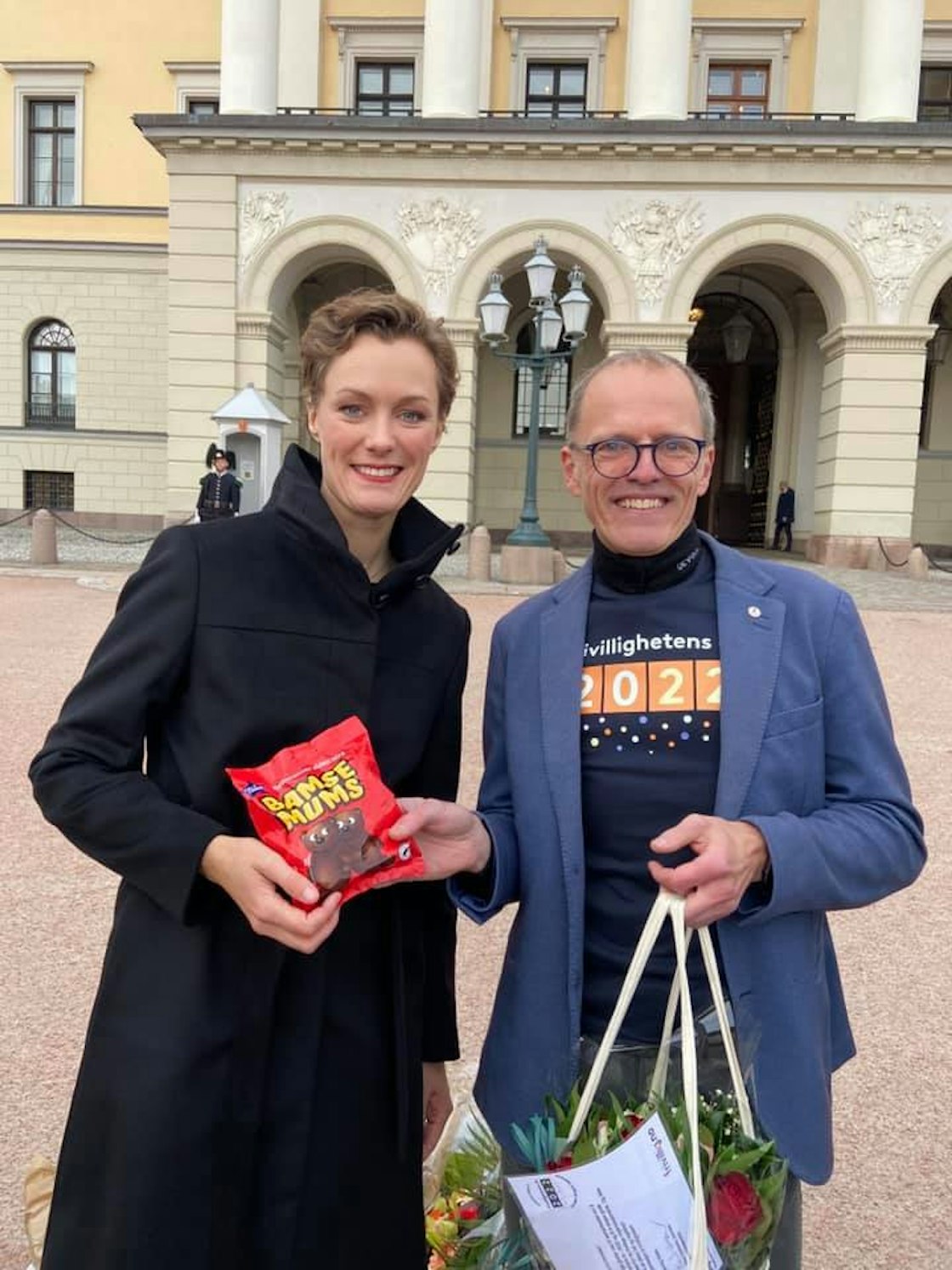 Kulturministeren og generalsekretæren i Frivillighet Norge smiler til kamera med en pose bamsemums