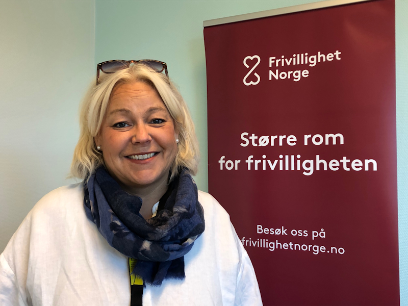 Birgitte Brekke foran rollup med Frivillighet Norge logo