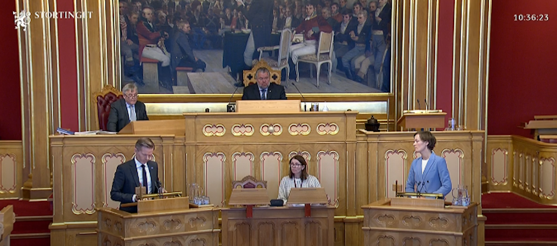 to personer ved mindre talestoler foran Stortingets talestol/dirigentbord.