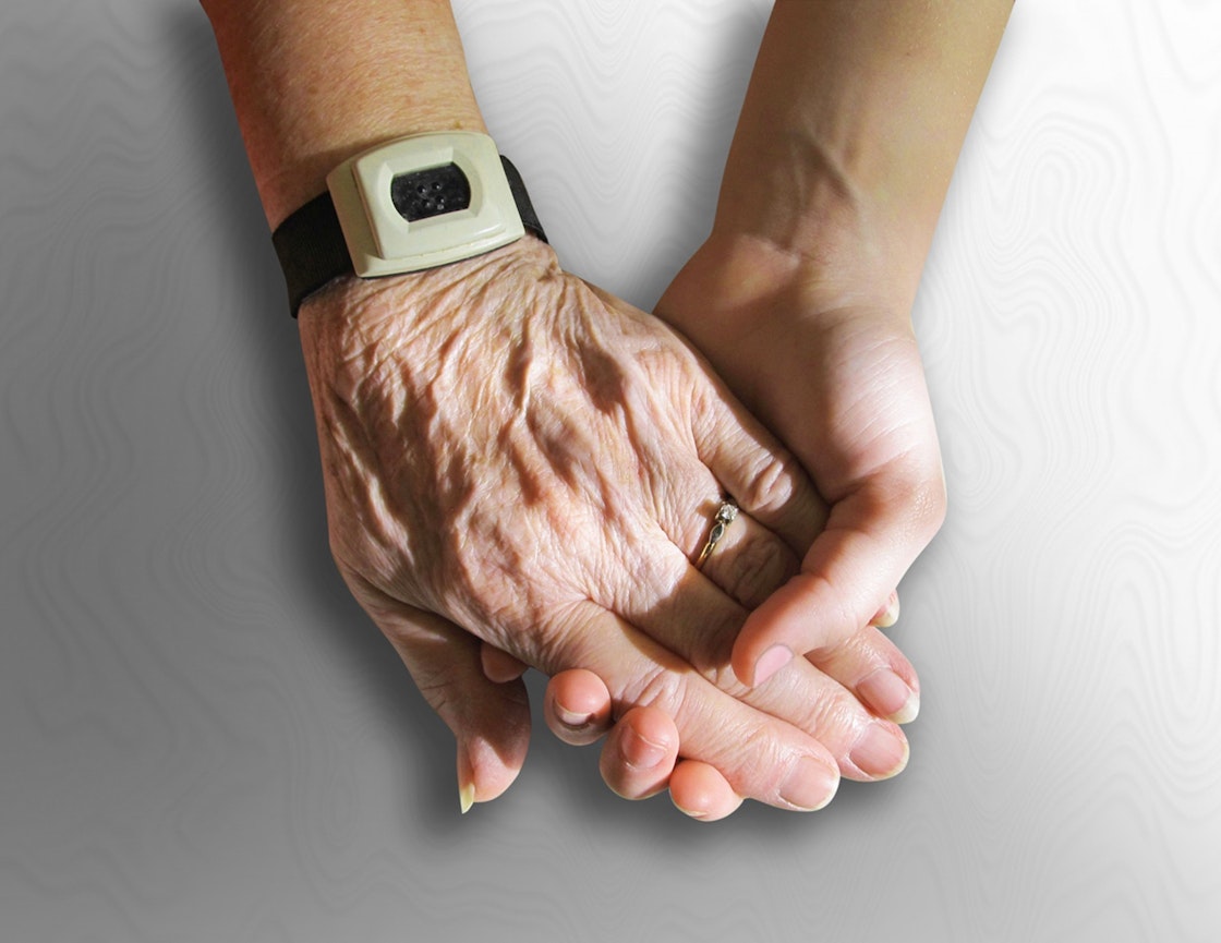 En eldre og yngre person holder hender. Nærbilde av hendene.
