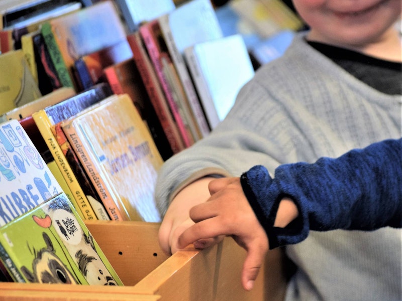 hendene til to barn foran kasse med bøker.