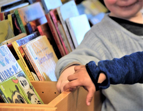 hendene til to barn foran kasse med bøker.