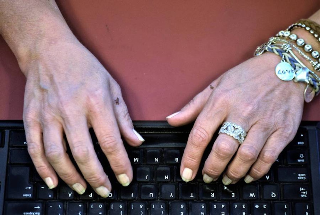 Hender med neglelagg, ring og armbånd skriver på tastatur