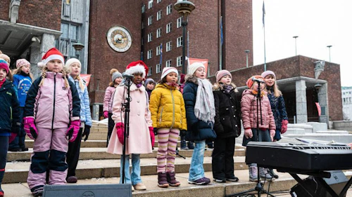 Barn står på rådhustrappa og synger